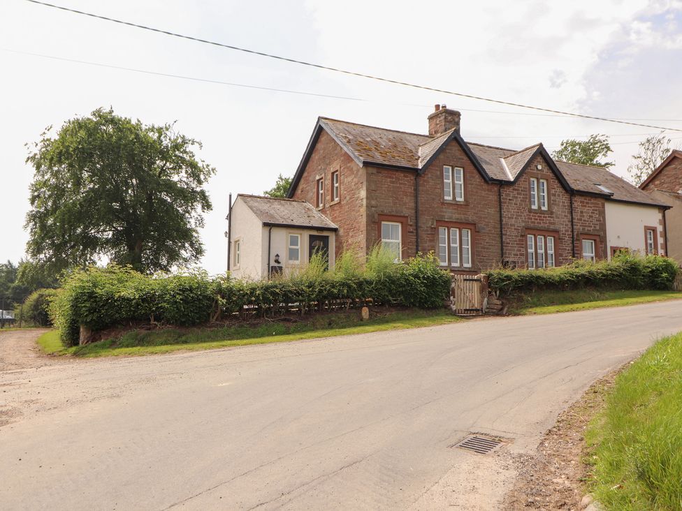 A house beside a road with trees and a hedge at Rose Bank Cottage Dalston