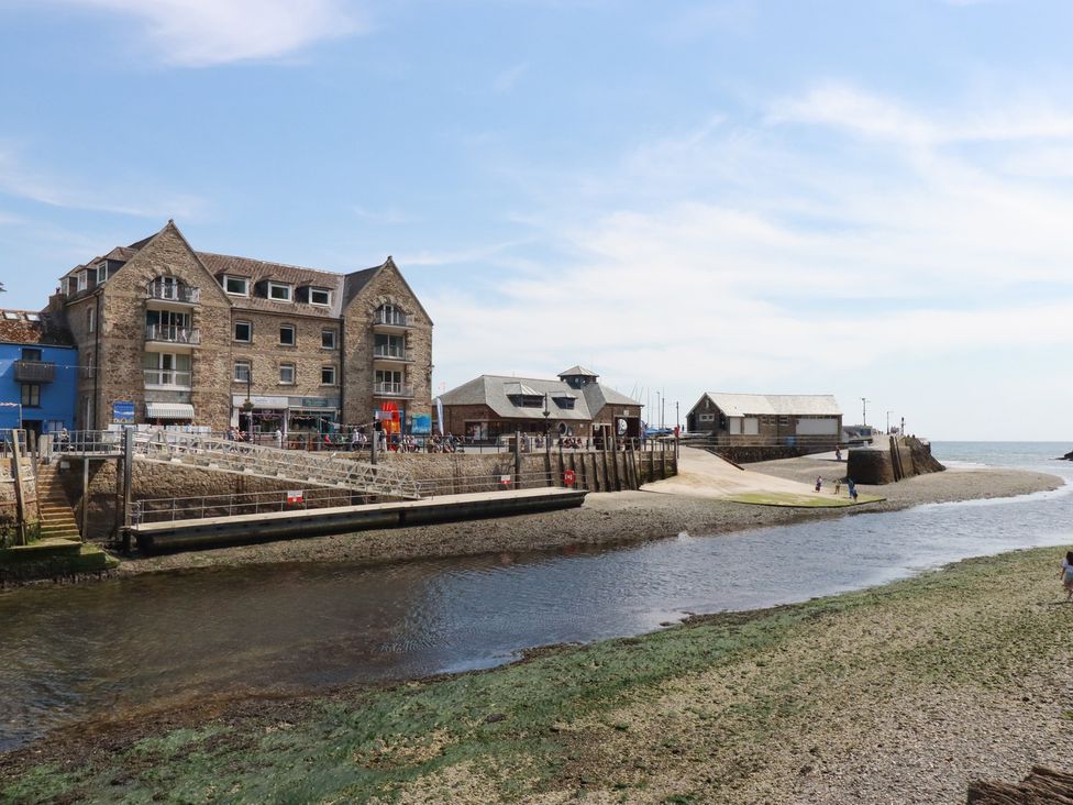 A river with stone buildings and a small pier by the sea at 3 River View in Looe