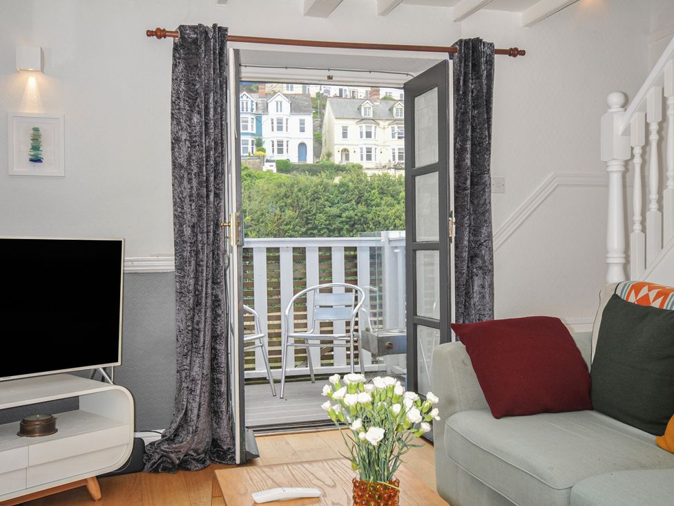A living room with a TV and a sliding door at 3 River View Looe