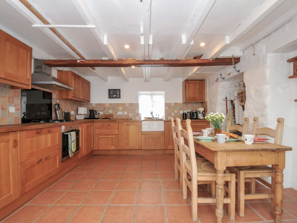 A kitchen with wooden cabinets and a table at 3 River View in Looe