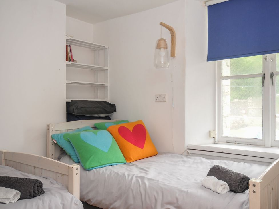 A bedroom with two beds and a shelf at 3 River View in Looe