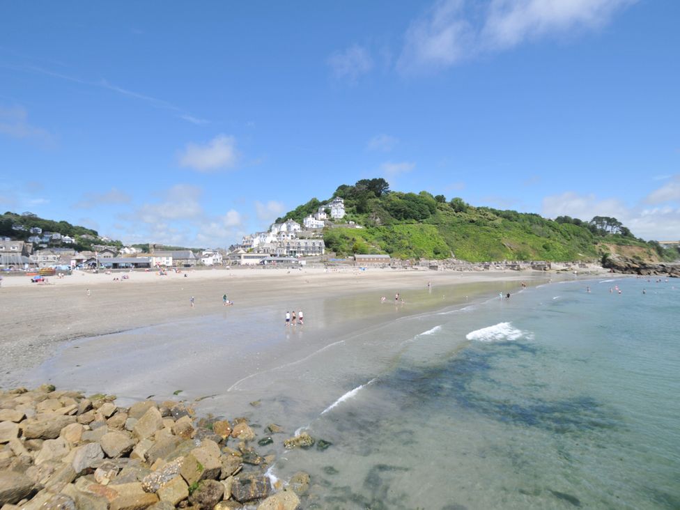 A beach with people and a view of houses on a hill at 3 River View in Looe