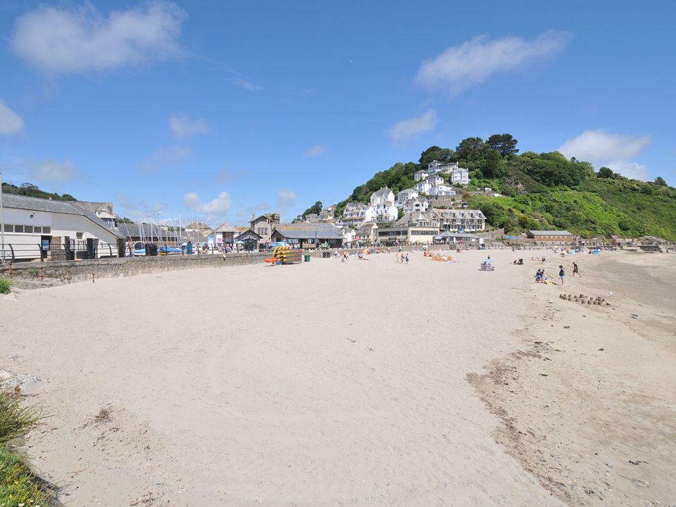 A beach with buildings and people at 3 River View in Looe