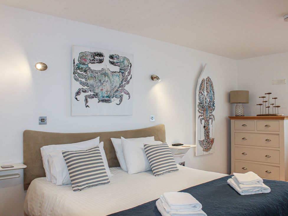A bedroom with a bed and artwork at 5 Harbour Yard in Salcombe