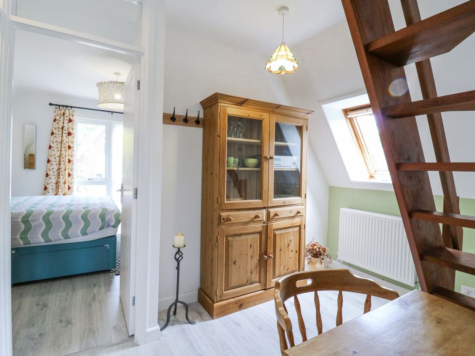 A room with a wooden cabinet a wooden chair and table and an open door to a bedroom at Kingfisher Isleham
