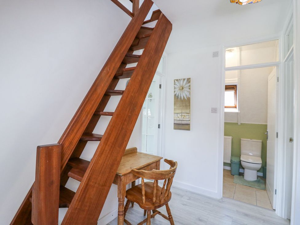 A wooden staircase next to a small wooden desk and chair with a bathroom visible through an open door at Kingfisher in Isleham