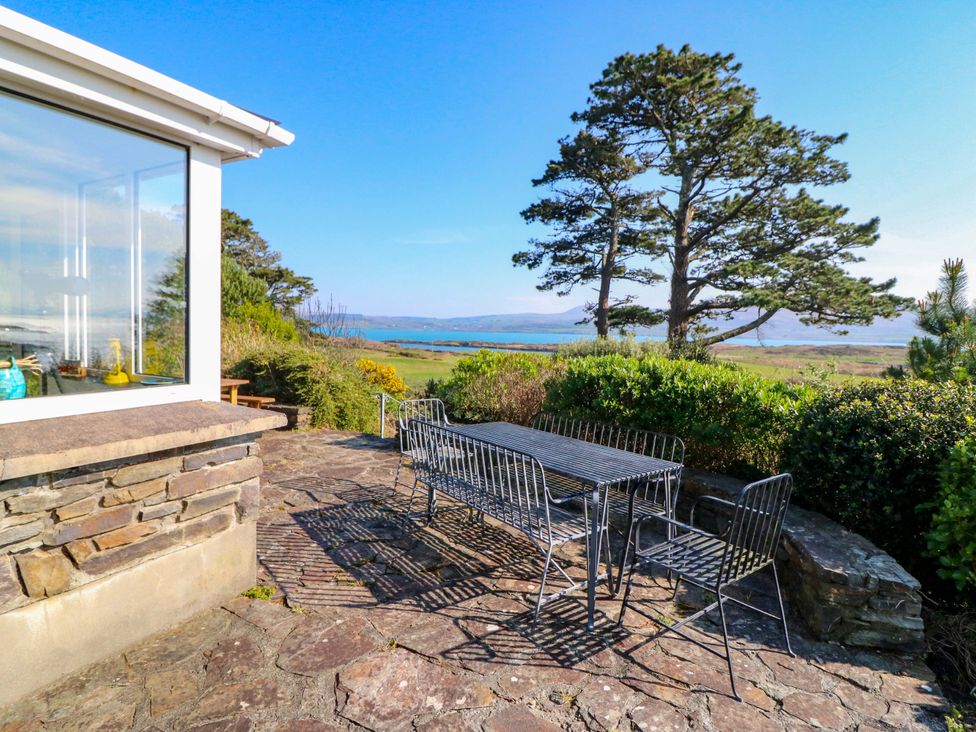 An outdoor area with a table and chairs overlooking the sea at Whispering Pines, Durrus, County Cork