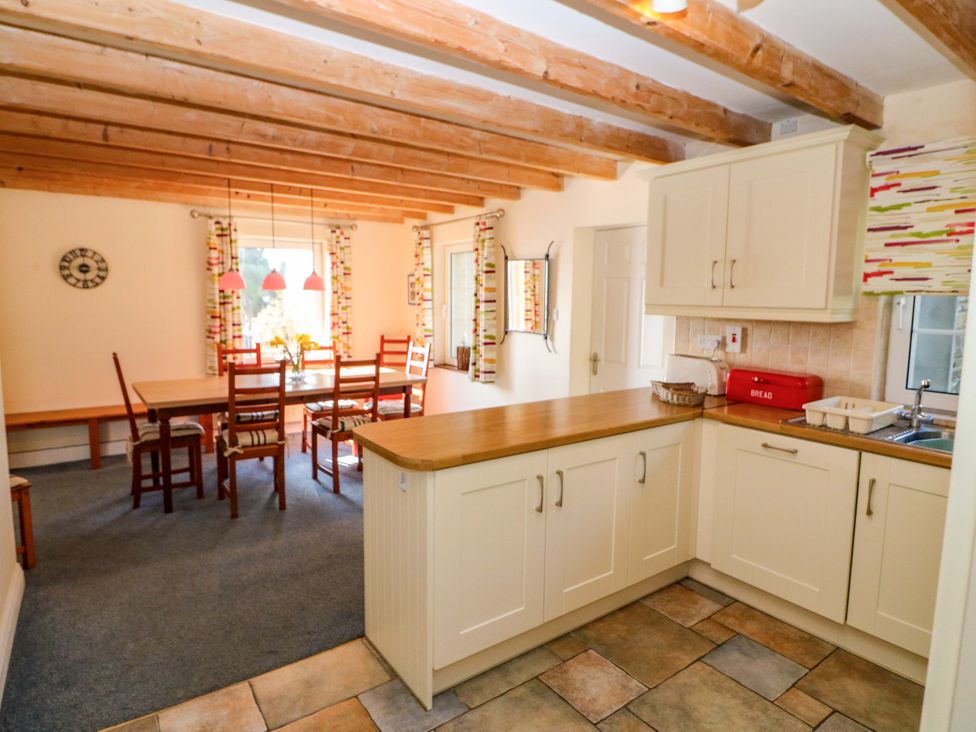 A kitchen with cabinets and a dining table at Whispering Pines in Durrus, County Cork
