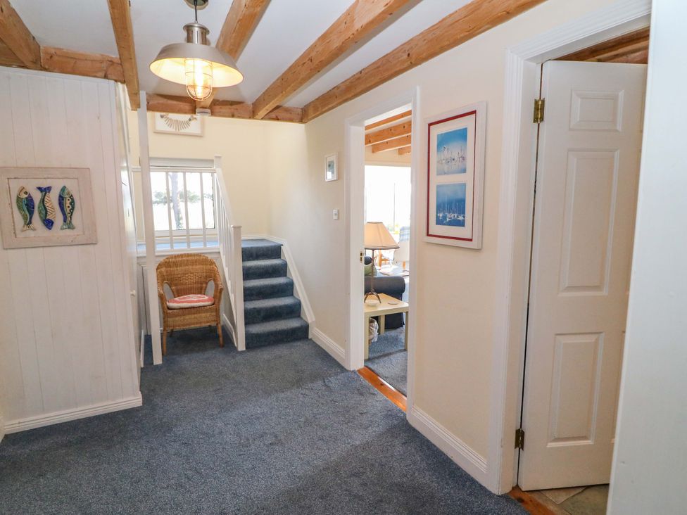 A hallway with a staircase and a wicker chair at Whispering Pines in Durrus, County Cork