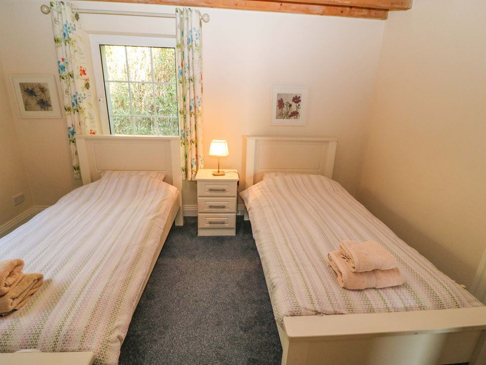 A bedroom with two beds and a lamp at Whispering Pines in Durrus, County Cork