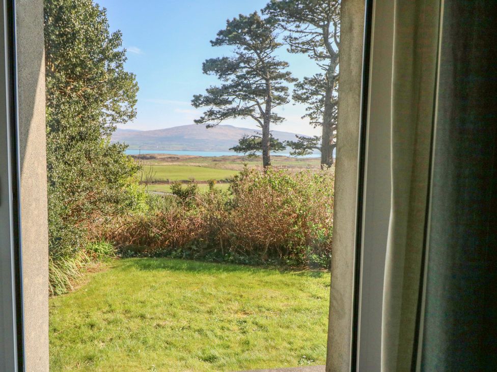 A view of trees and a garden with water in the background at Whispering Pines in Durrus, County Cork