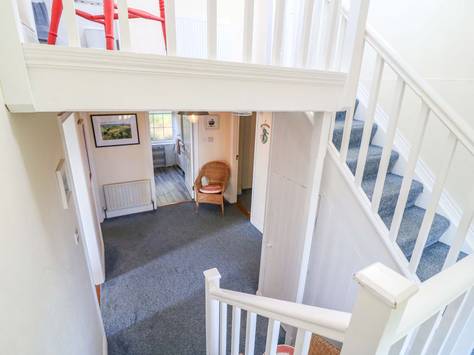 A hallway with a staircase and chair at Whispering Pines in Durrus, County Cork