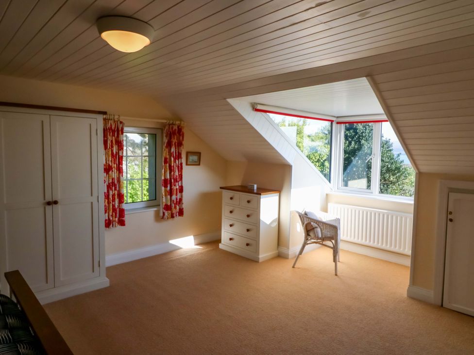 A bedroom with a wardrobe and a window at Whispering Pines, Durrus, County Cork