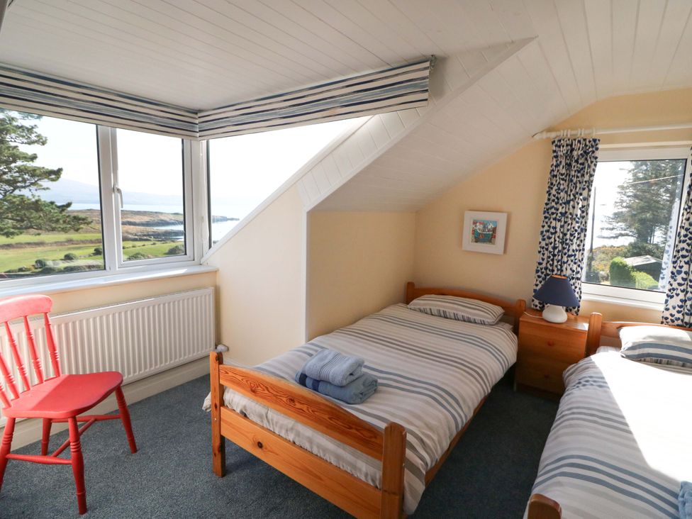 A bedroom with two beds and a red chair at Whispering Pines in Durrus, County Cork