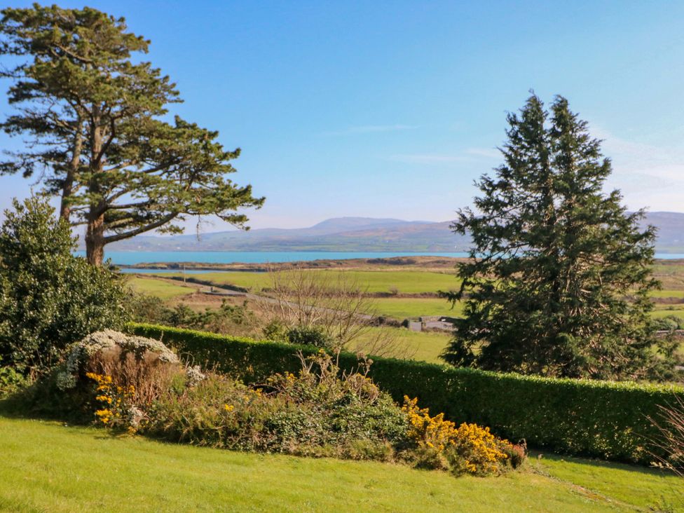 A garden with trees and bushes overlooking the sea at Whispering Pines in Durrus, County Cork