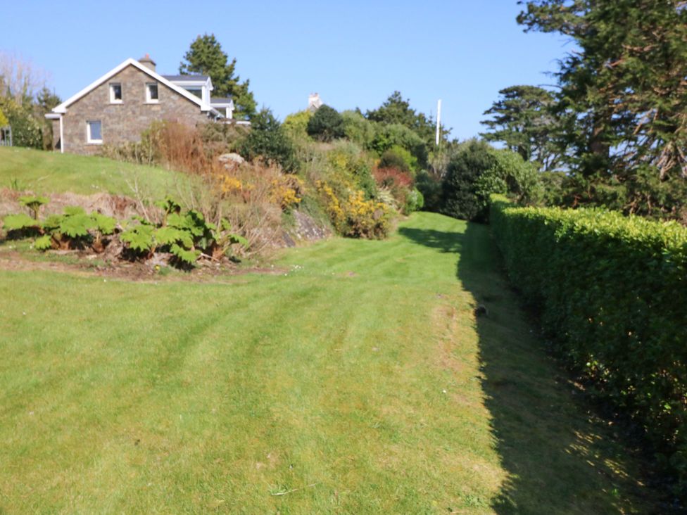 A garden with a house and pathway at Whispering Pines in Durrus, County Cork