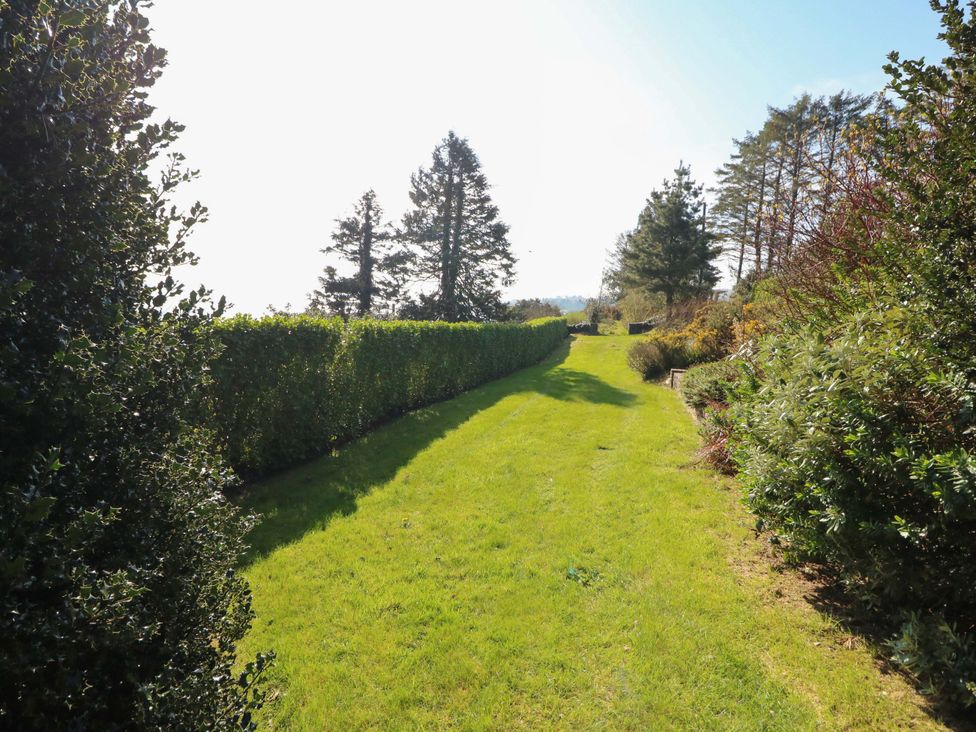 A garden with a pathway bordered by hedges and trees at Whispering Pines Durrus, County Cork