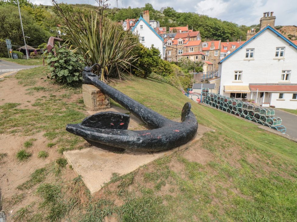 An anchor on a grassy area with buildings in the background at Lilac Lodge in Runswick Bay near Staithes