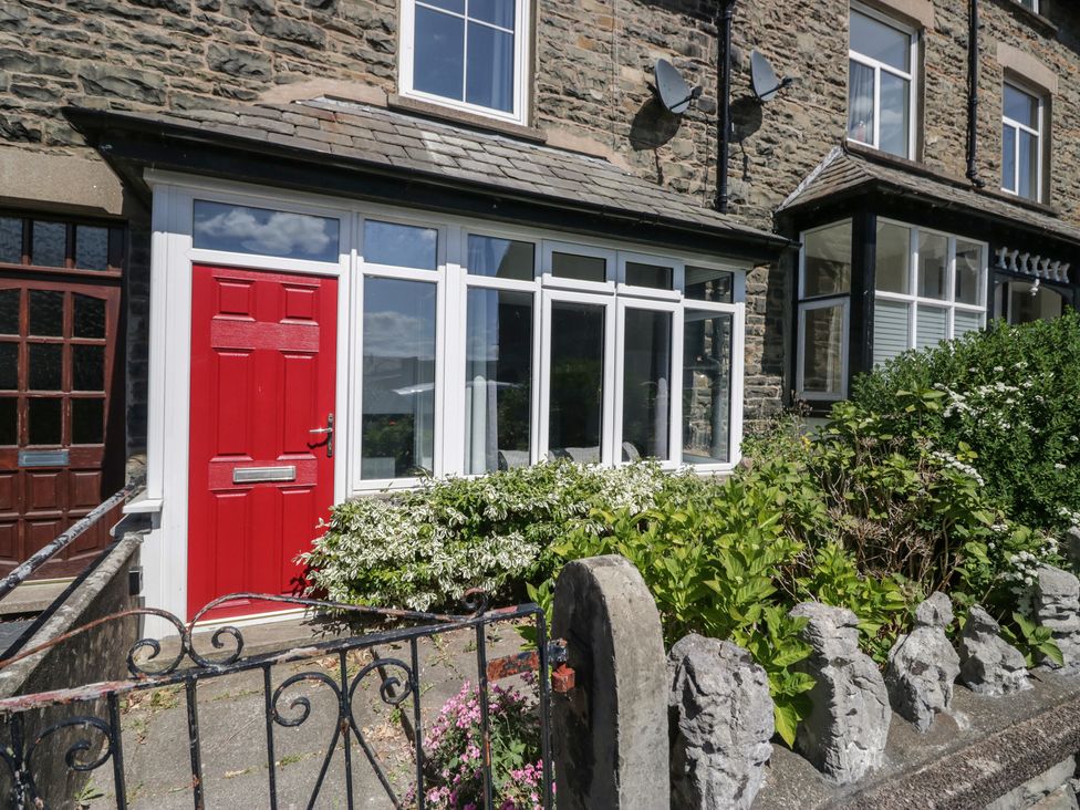 A front entrance with a red door and flowers at Badgers, Sedbergh, Yorkshire Dales