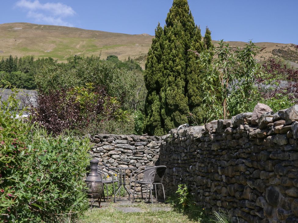 A garden with a stone wall and furniture at Badgers, Sedbergh, Yorkshire Dales