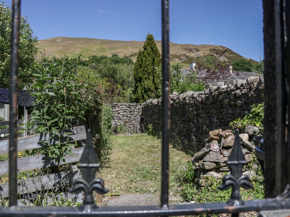 A garden with a stone wall and chairs at Badgers in Sedbergh, Yorkshire Dales
