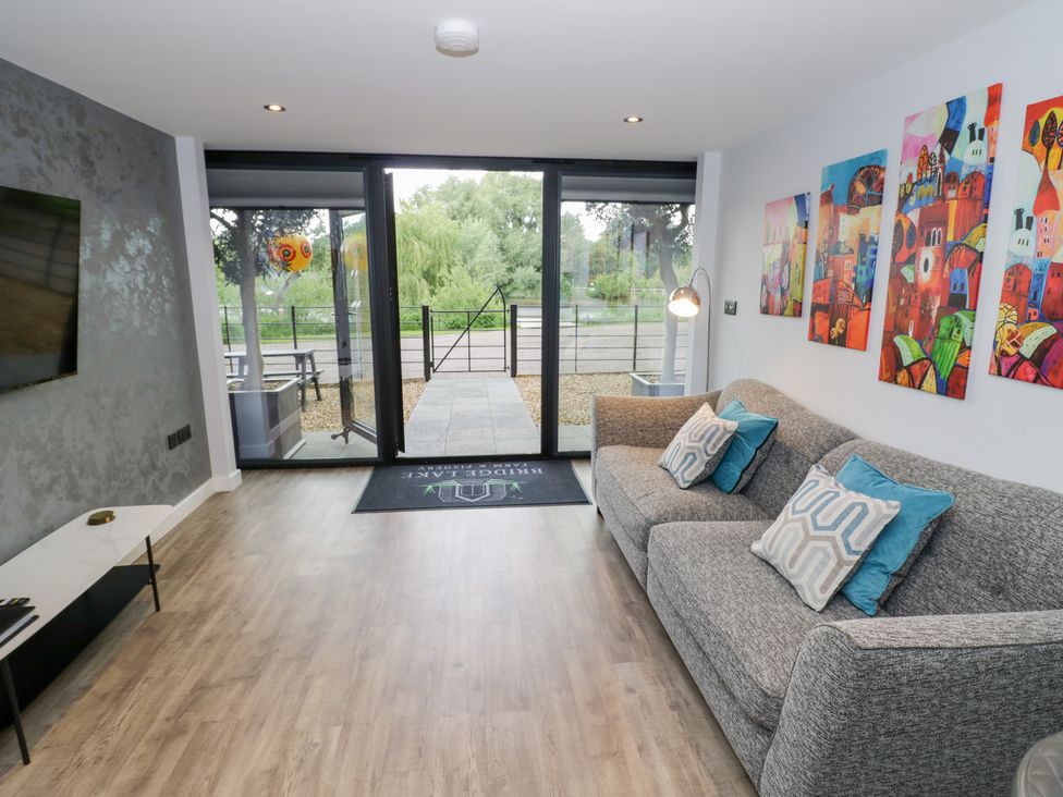A living room with a sofa and paintings at The Tunnel at Bridge Lake Farm and Fishery Chacombe