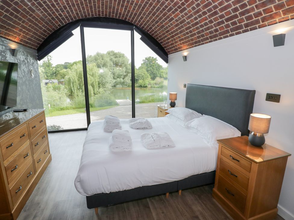 A bedroom with a bed and lake view at The Tunnel at Bridge Lake Farm and Fishery Chacombe