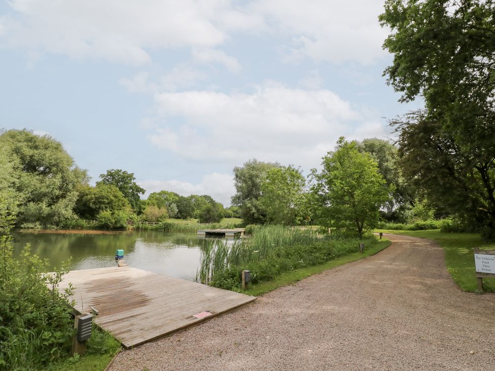 A scenic view of a water body with a dock and a pathway at The Tunnel at Bridge Lake Farm and Fishery Chacombe