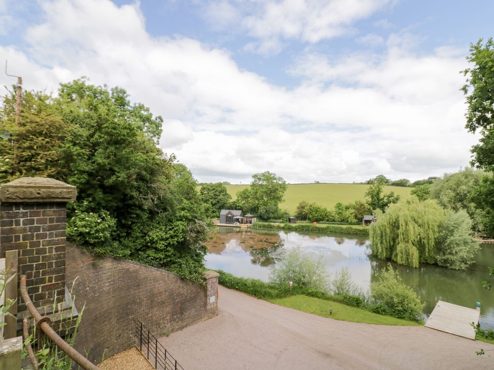 A lake with trees and buildings near the shore at The Tunnel at Bridge Lake Farm and Fishery Chacombe