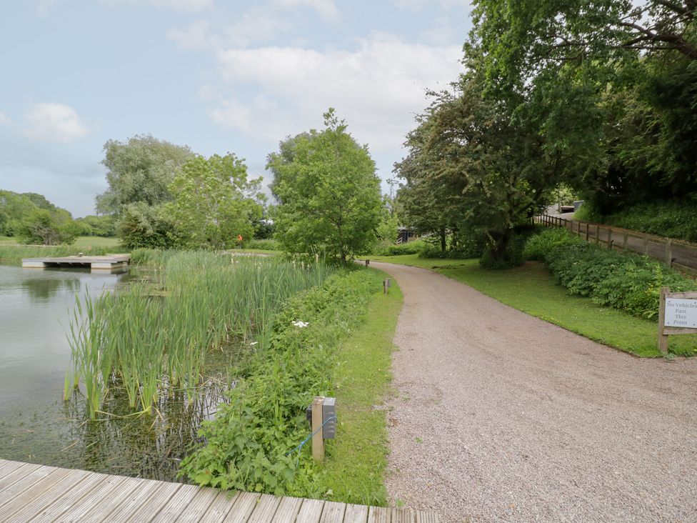 A path alongside water and greenery at The Tunnel at Bridge Lake Farm and Fishery Chacombe