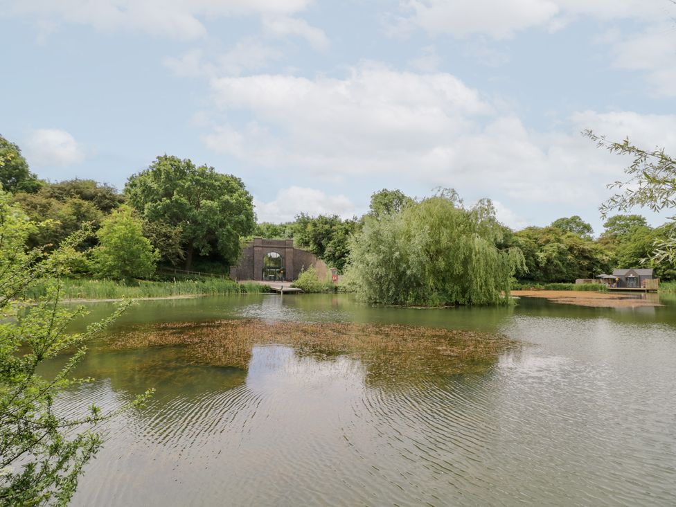 A large lake with an island and trees at The Tunnel at Bridge Lake Farm and Fishery Chacombe