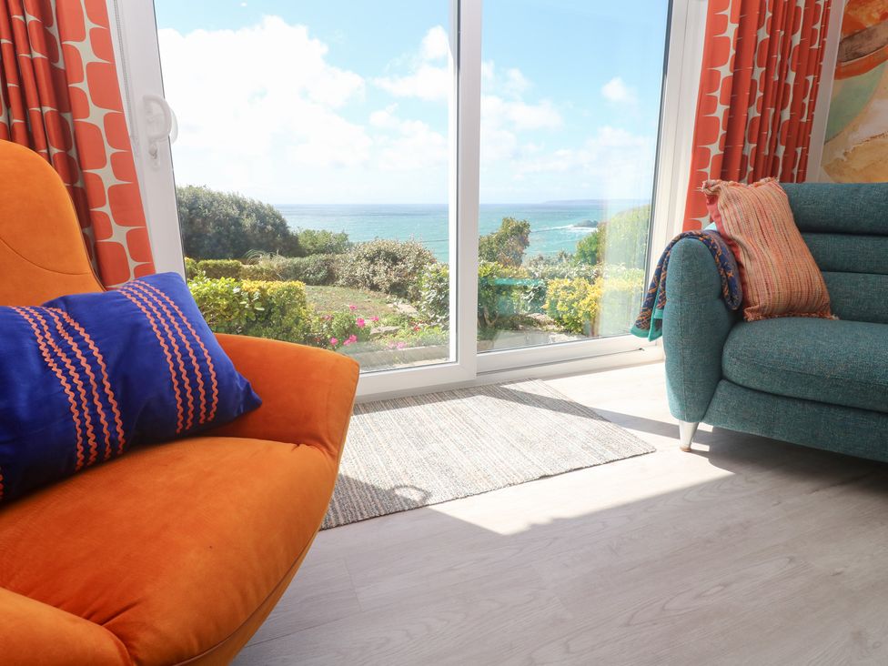 A living room with orange chair and teal sofa at Shearwater