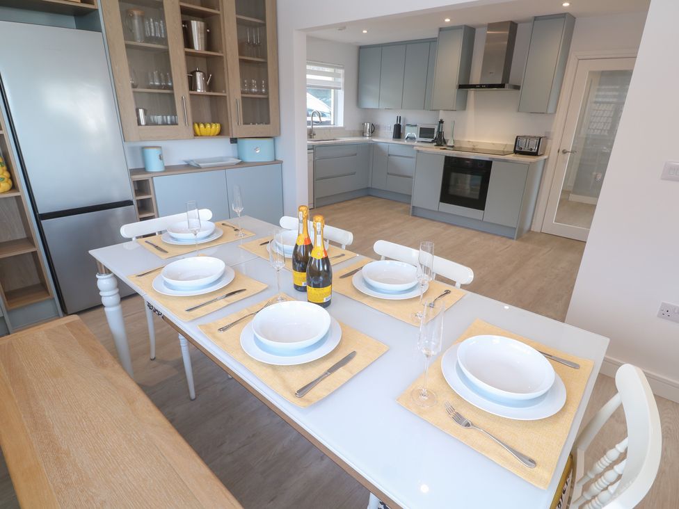 A dining area with a table set and kitchen in Shearwater