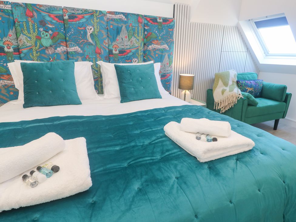 A bedroom with a bed, pillows, and armchair at Shearwater 