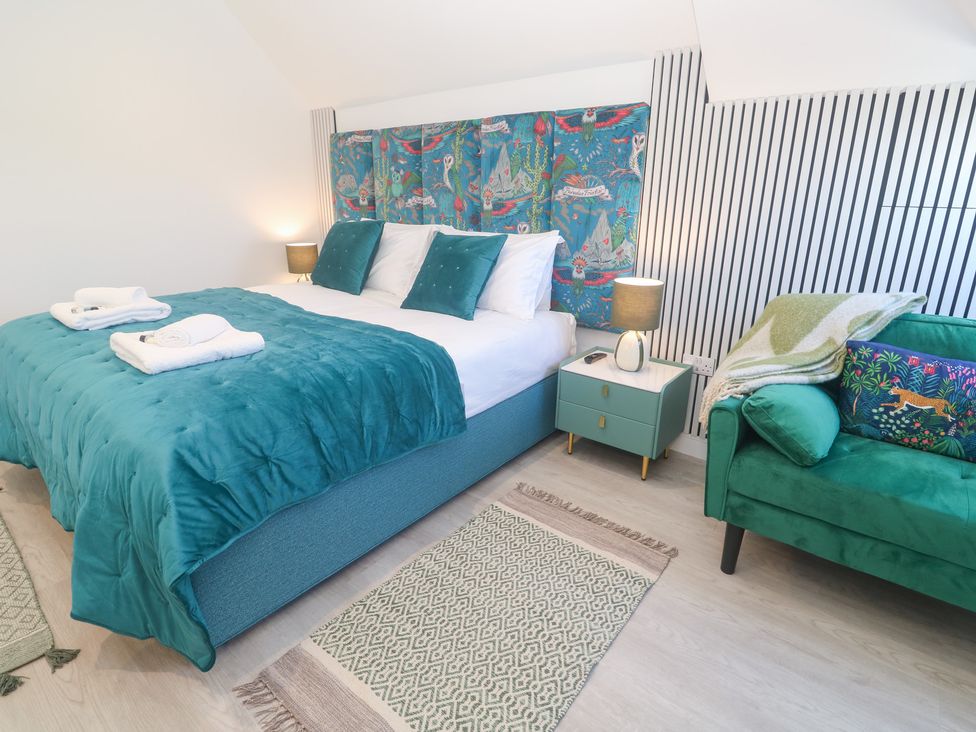 A bedroom with a bed and a green sofa at Shearwater