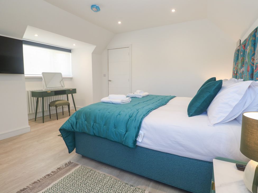 A bedroom with a bed, mirror, and table at Shearwater