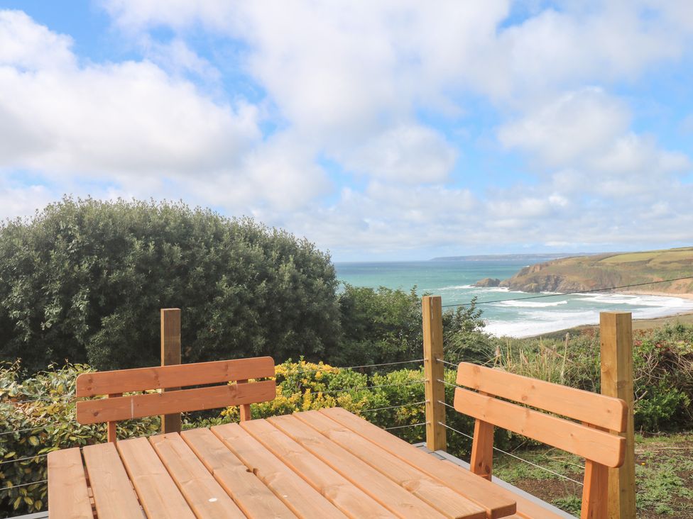 An outdoor seating area with a table and bench overlooking the ocean at Shearwater