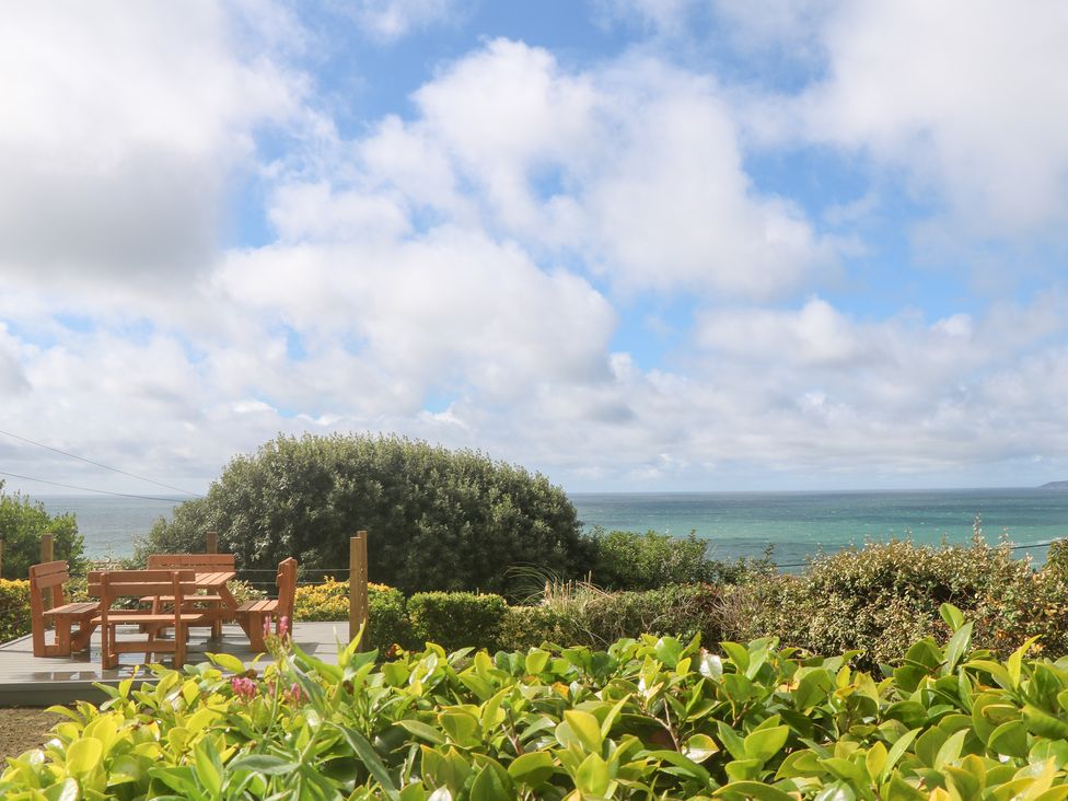 An outdoor space with a table and benches overlooking the sea at Shearwater