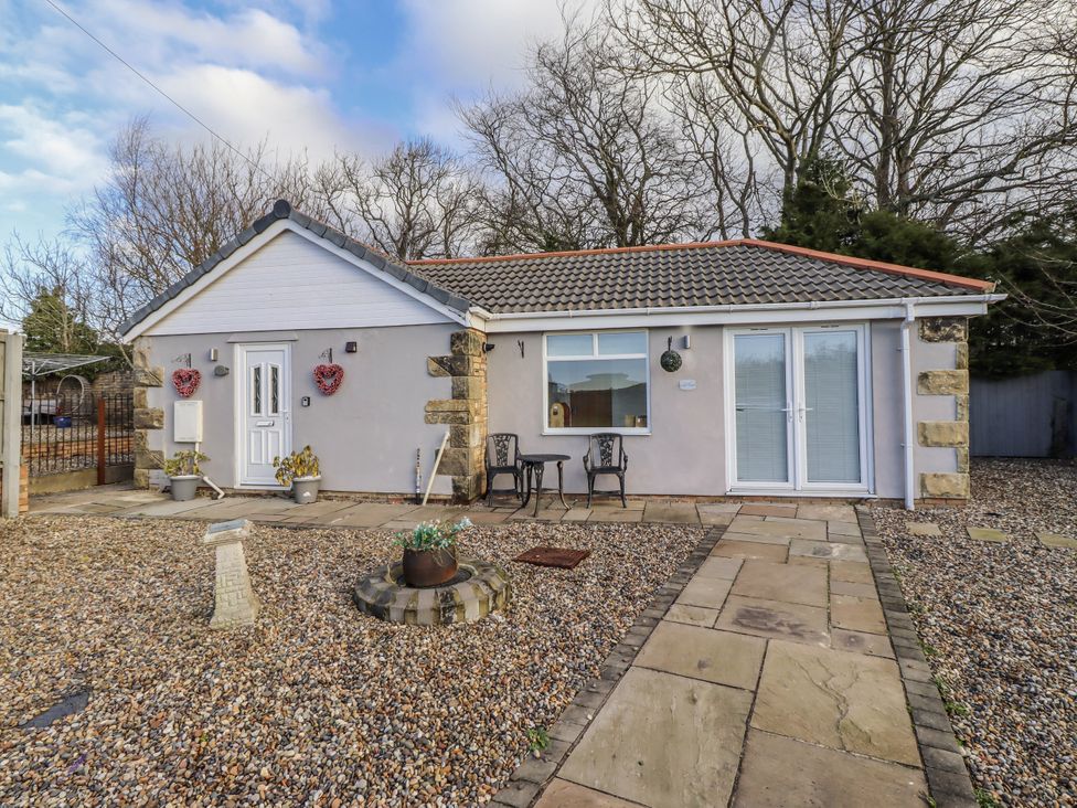 An outdoor area with a house and chairs at Old Colliery Cottage in Shilbottle