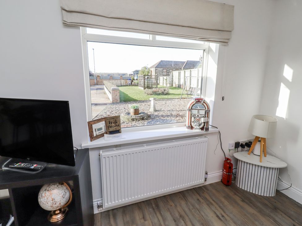 A living room with a television and a window overlooking the garden at Old Colliery Cottage in Shilbottle