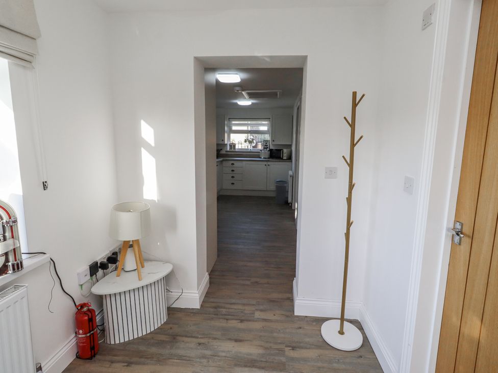 A hallway with a lamp and coat rack at Old Colliery Cottage in Shilbottle