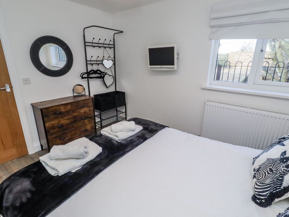 A bedroom with towels and a television at Old Colliery Cottage in Shilbottle