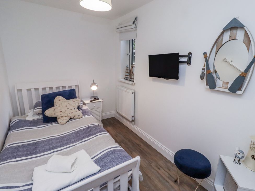 A bedroom with a bed and a wall-mounted television at Old Colliery Cottage in Shilbottle