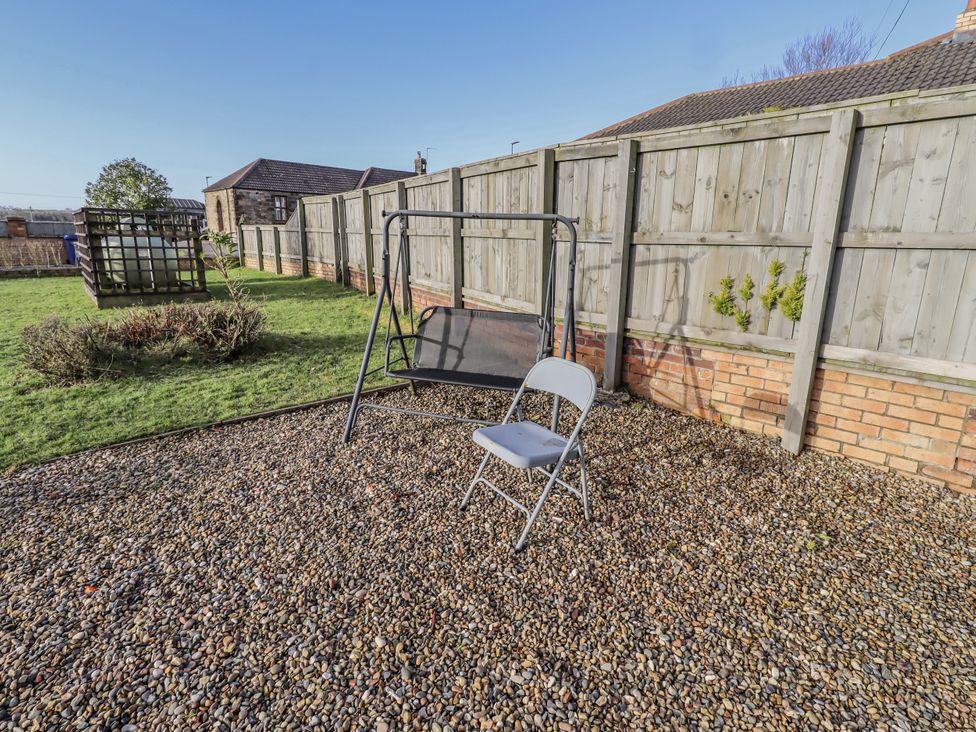 A garden with a swing chair and folding chair at Old Colliery Cottage in Shilbottle