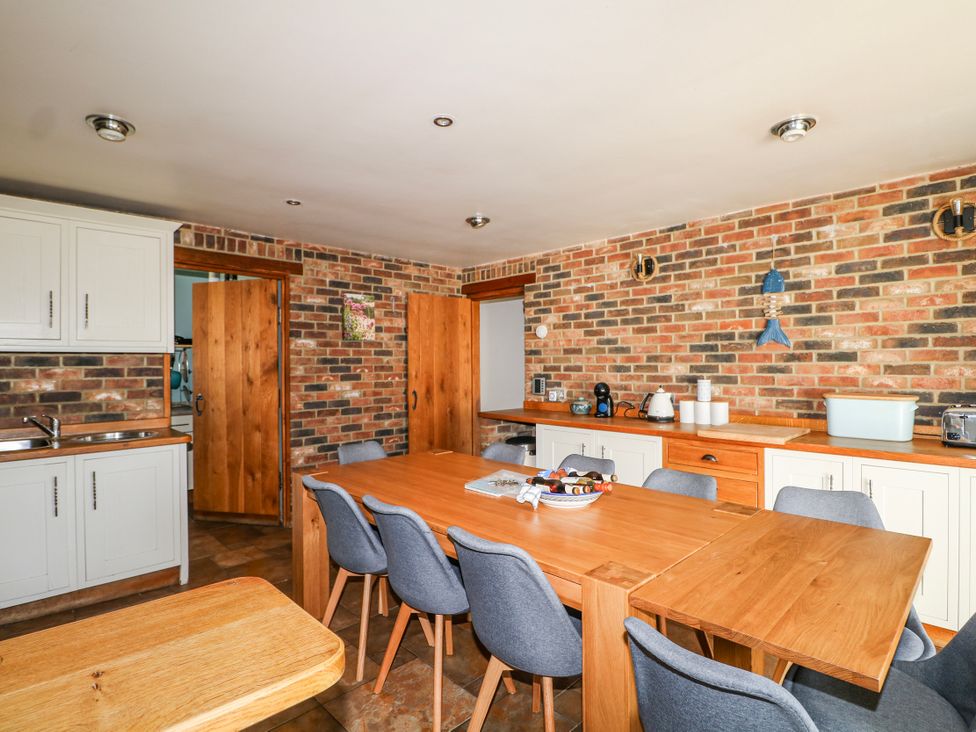 A kitchen with a wooden table and chairs at 50 Harbour Road in Pagham