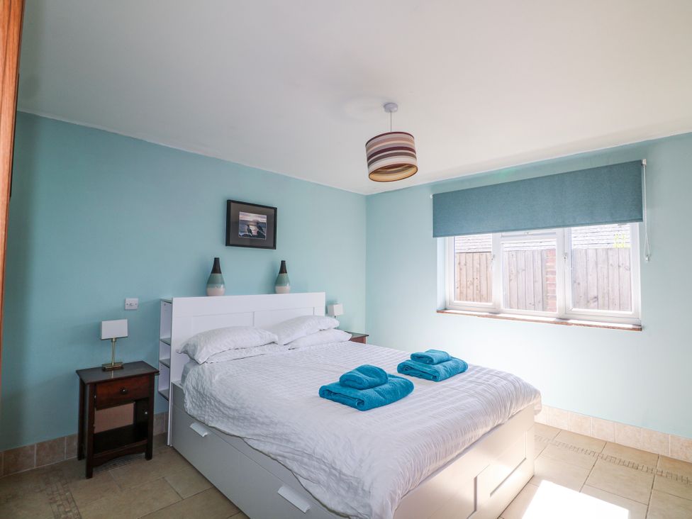 A bedroom with a bed and bedside tables at 50 Harbour Road in Pagham