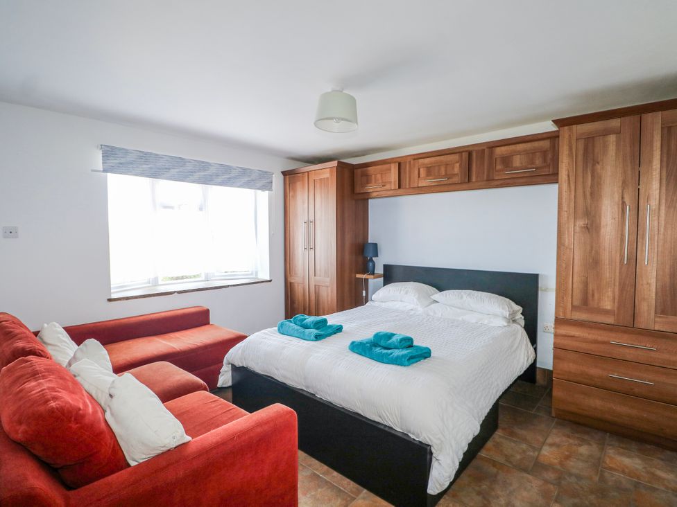 A bedroom with a bed and sofa at 50 Harbour Road in Pagham