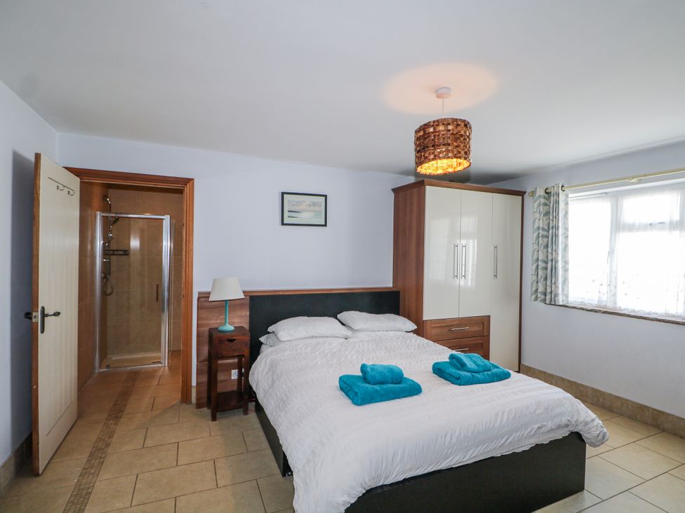 A bedroom with a bed and shower enclosure at 50 Harbour Road Pagham