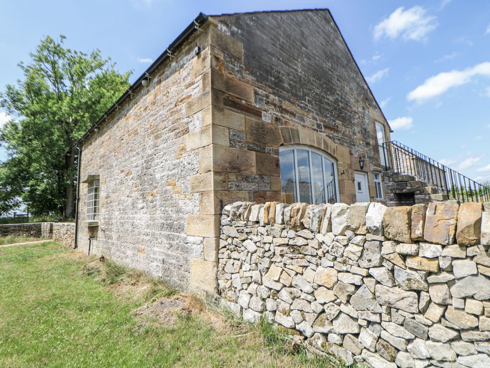 A building with a stone wall and grass at The Coach House at Mayfurlong Farm Grindon near Waterhouses