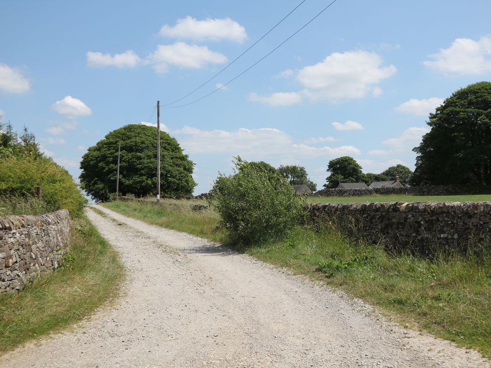 A dirt road surrounded by trees and stone walls at The Coach House at Mayfurlong Farm, Grindon near Waterhouses